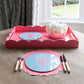 Large pink lacquer tray with a scalloped edge on a dining room table