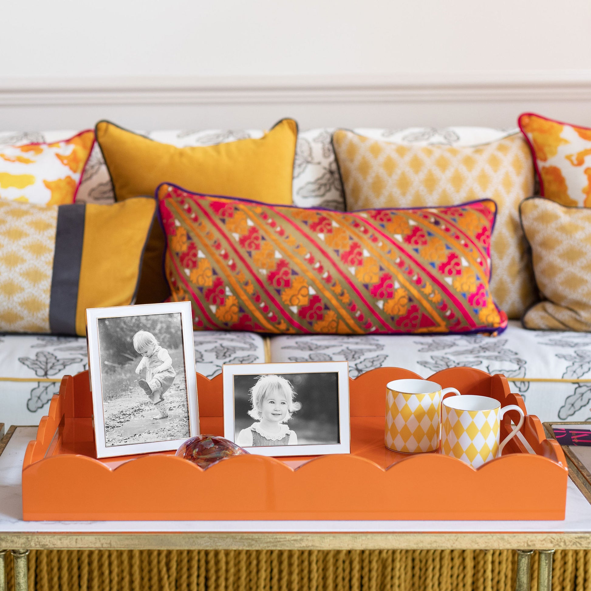 Photo frames and tea cups on a large orange lacquer tray 
