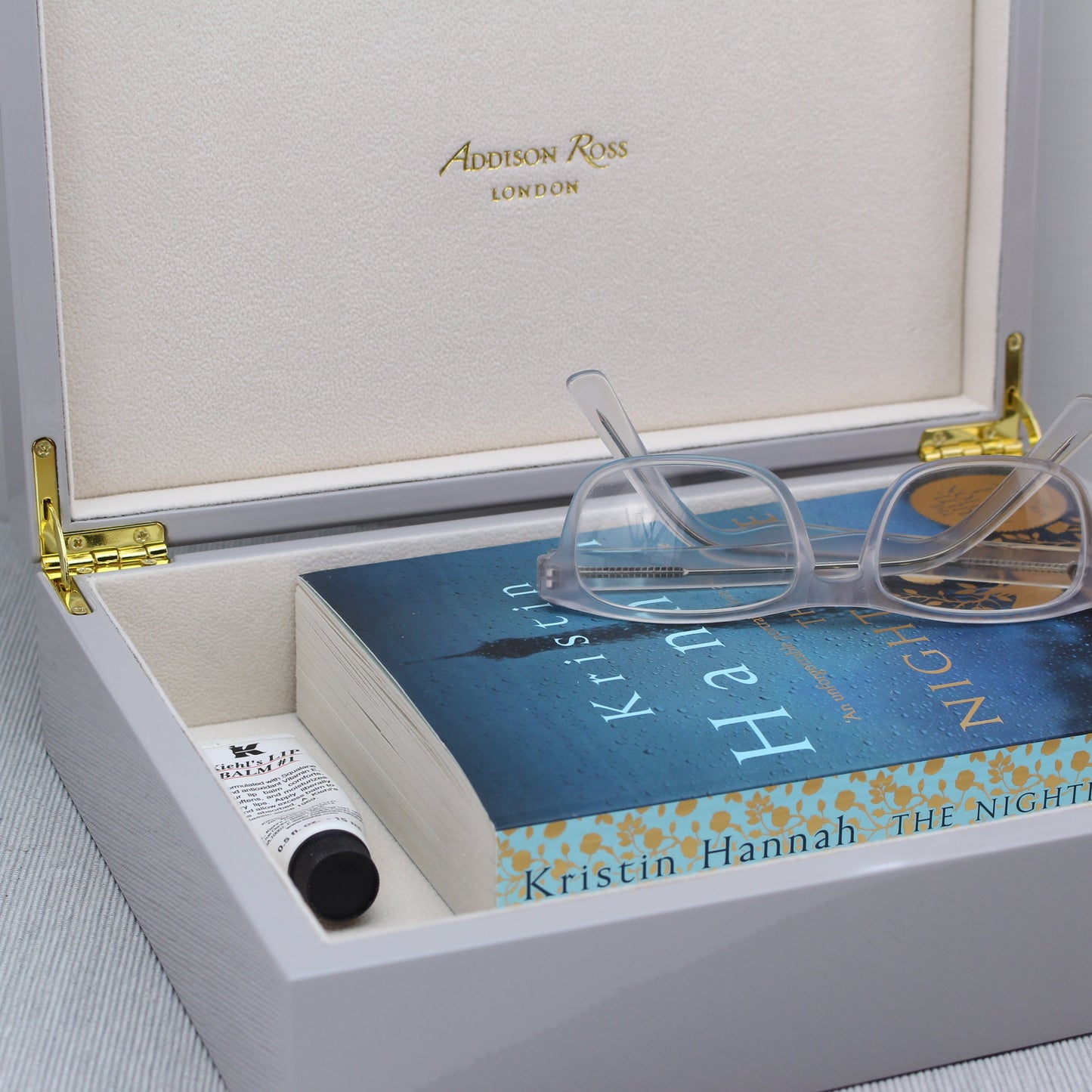 A book and reading glasses in a white storage box
